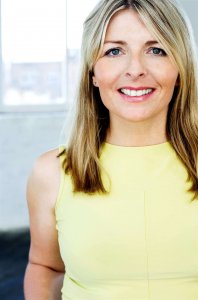 The image shows a woman smiling with a yellow colored dress.