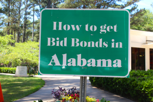 Green sign in a sunny park with the message 'How to get Bid Bonds in Alabama,' emphasizing the process of obtaining bid bonds in the state.