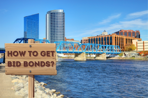 Scenic view of a city in Michigan with a wooden sign that reads 'How to Get Bid Bonds?' with a blue bridge and modern buildings in the background.