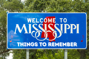 Welcome to Mississippi road sign with the caption 'Things to Remember', framed by trees in the background.