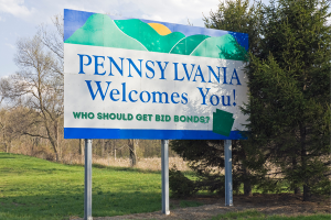 Pennsylvania Welcomes You - Signage on a Pennsylvania state border welcoming visitors with a question about who should get bid bonds.