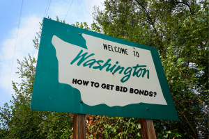 Green highway sign welcoming travelers to Washington, with the question 'How to Get Bid Bonds?' creatively displayed, symbolizing the steps and process of securing bid bonds in Washington.