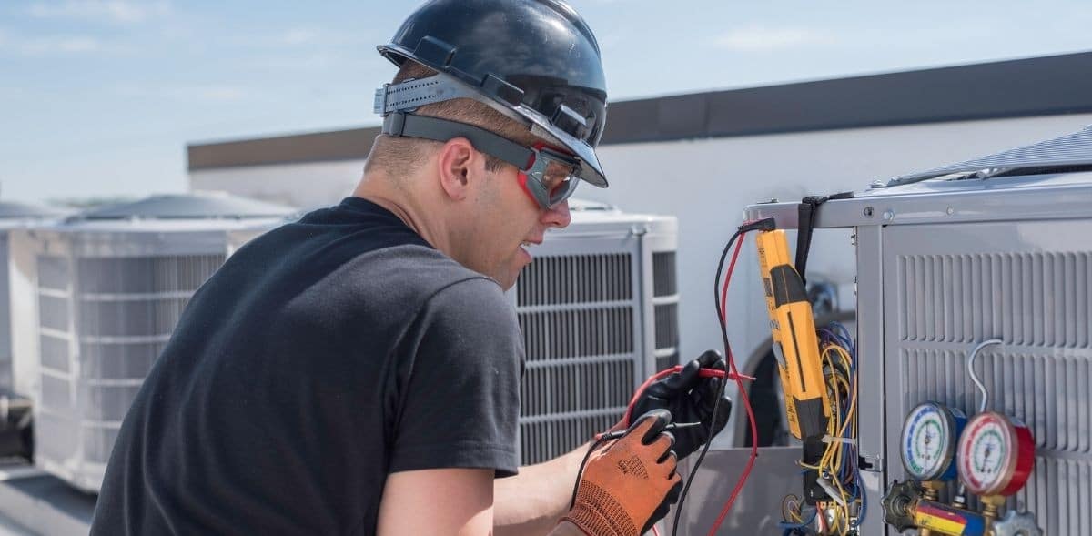 HVAC specialist testing rooftop air conditioning units using diagnostic tools.

