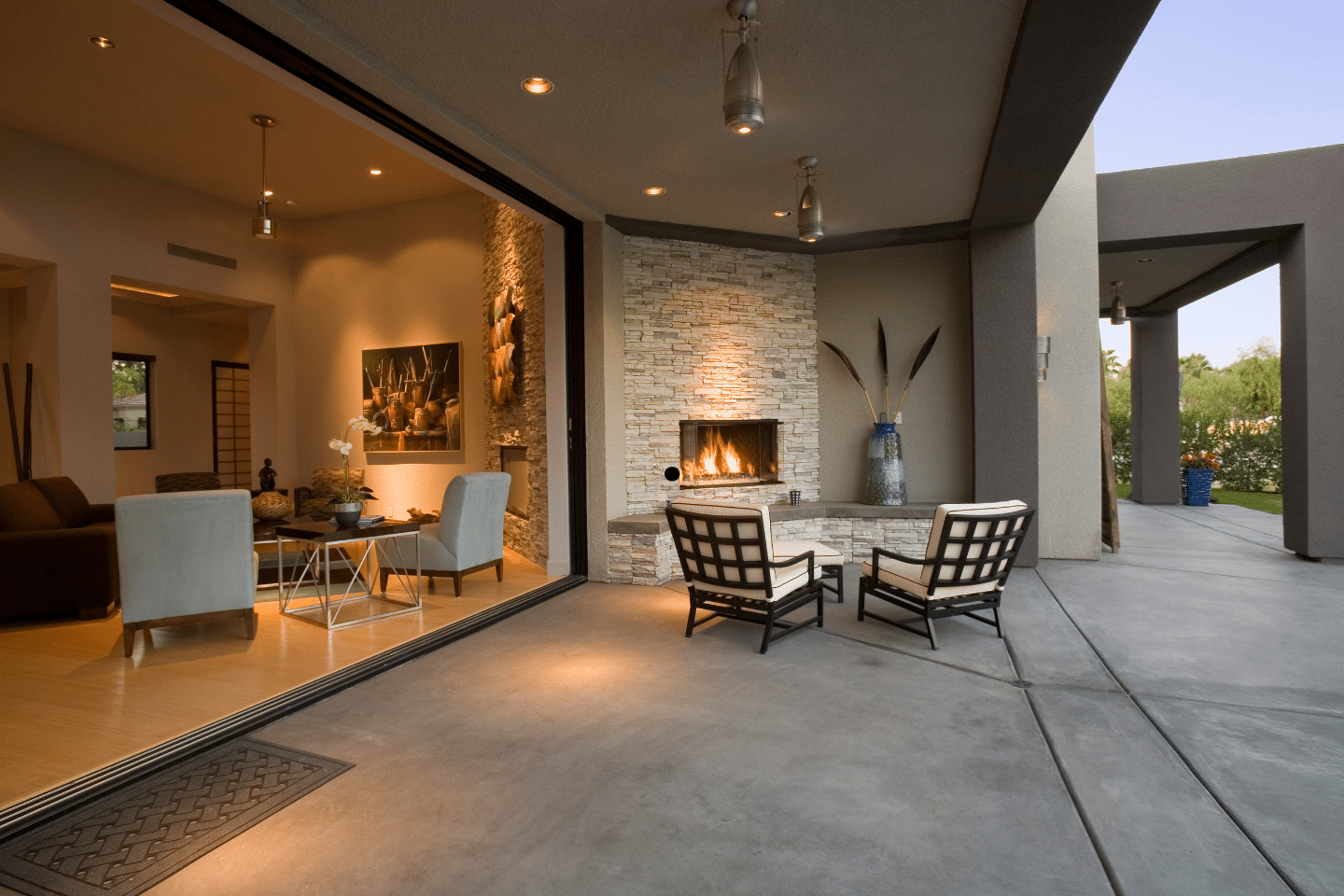 Modern open-concept living room with a cozy fireplace connecting to an outdoor patio area.