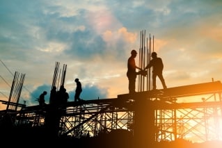 Performance bond Kansas - The image shows contractors working with a cloudy sky and a sun.