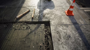 Fresh concrete sidewalk repair with construction tools and safety cone showing compliant sidewalk approach work in Sachse TX