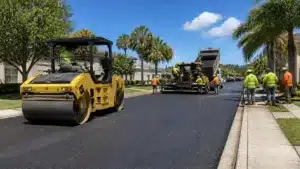 Heavy paving equipment and contractors completing asphalt resurfacing for an Escambia County, FL Road Restoration Permit ($10,000) Bond project.