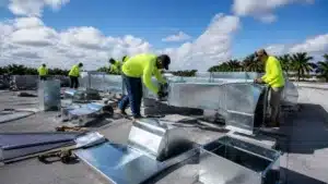 Construction workers installing rooftop HVAC ventilation ducts on a commercial property