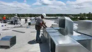Sheet metal technician fitting rooftop HVAC ductwork for work covered by an Osceola County Sheet Metal Limited ($5,000) Bond.