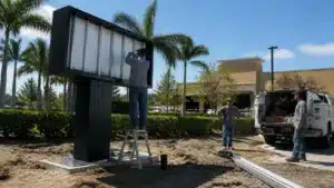 Commercial sign installation crew completing a non-electrical business sign installation in Florida outside a retail property.