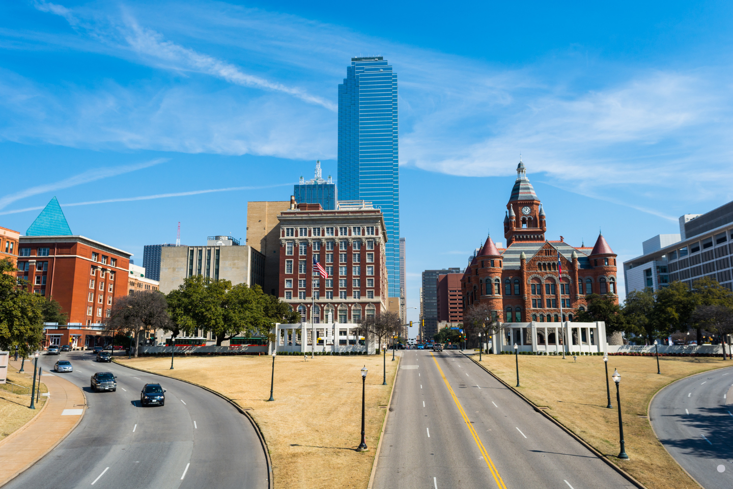 Curved divided roadway leading into a downtown area with a mix of historic and modern architecture.