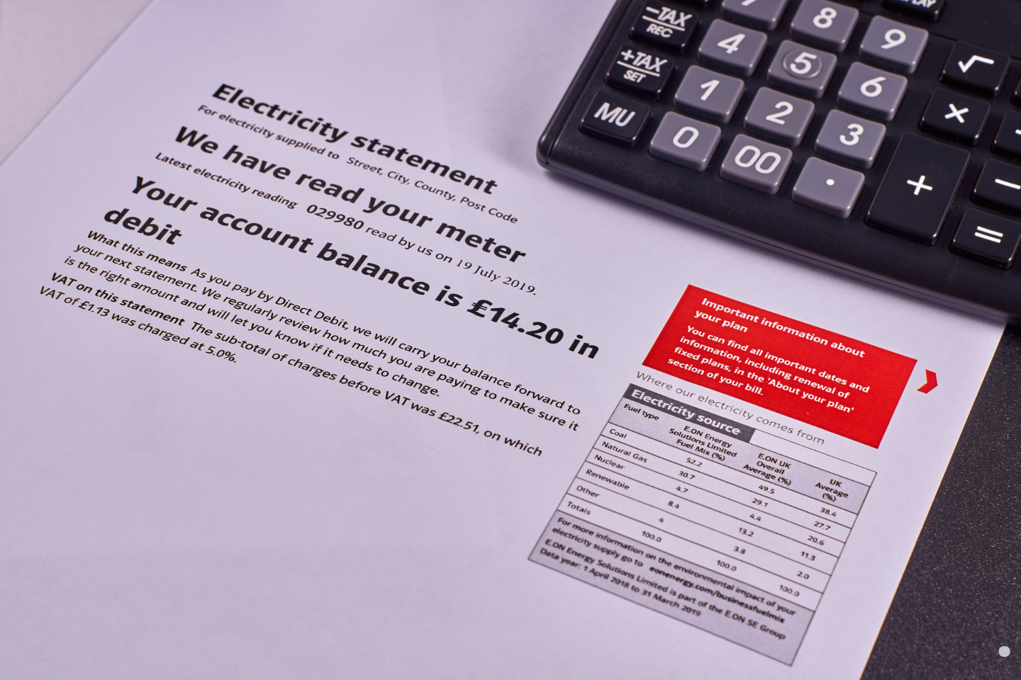 An electricity bill with account details and a calculator placed beside it.
