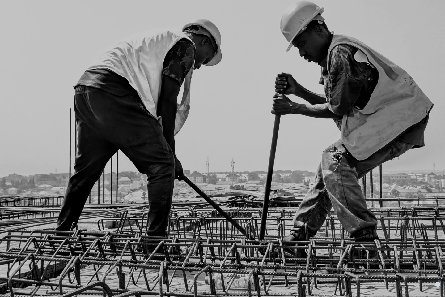 Construction workers installing steel reinforcement at a job site, representing regulated building and code compliance work.