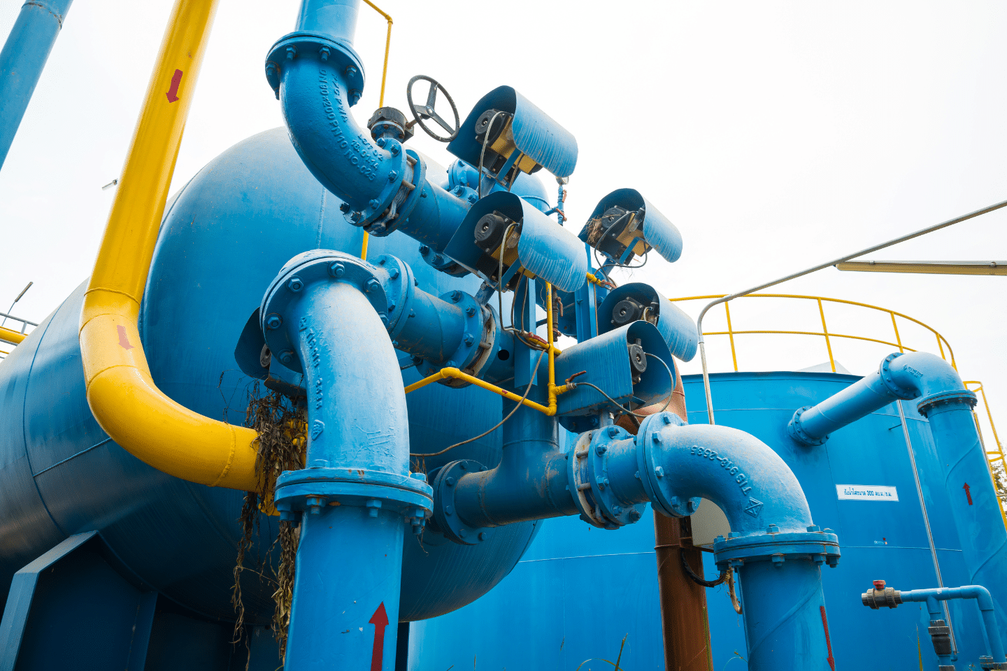 Outdoor water treatment system featuring large blue pipes and yellow support lines.