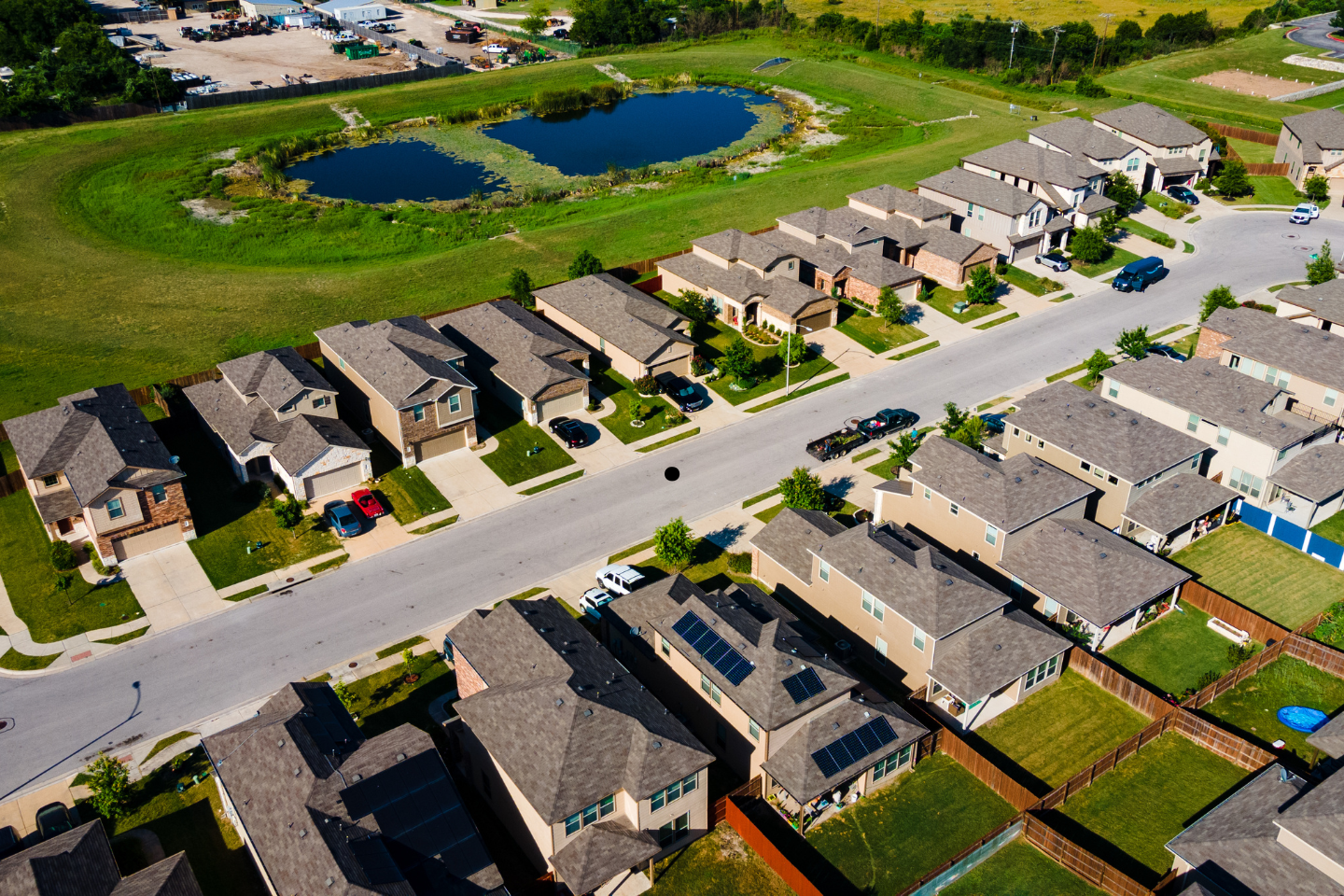 Aerial view of a suburban neighborhood with neatly aligned homes and nearby ponds.