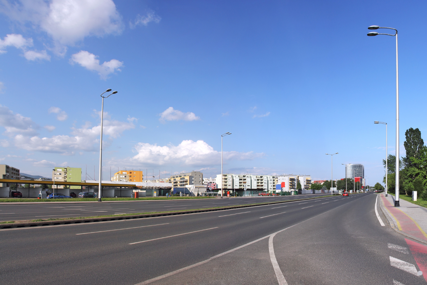 A broad multilane roadway curving through a modern urban district under a clear sky.