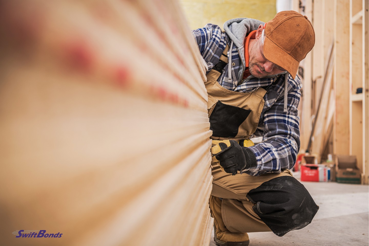 The general contractor in his uniform counts the pieces of drywall inside the currently under construction house.