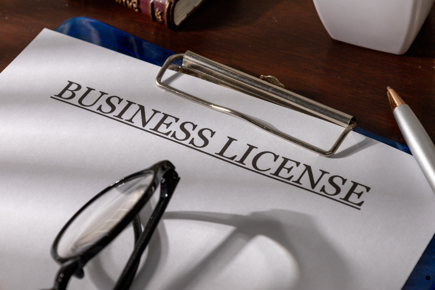 Business license form on a clipboard with eyeglasses and a pen nearby.