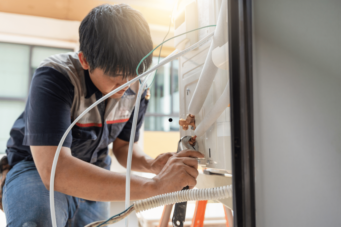HVAC worker connecting refrigerant lines to a cooling system.