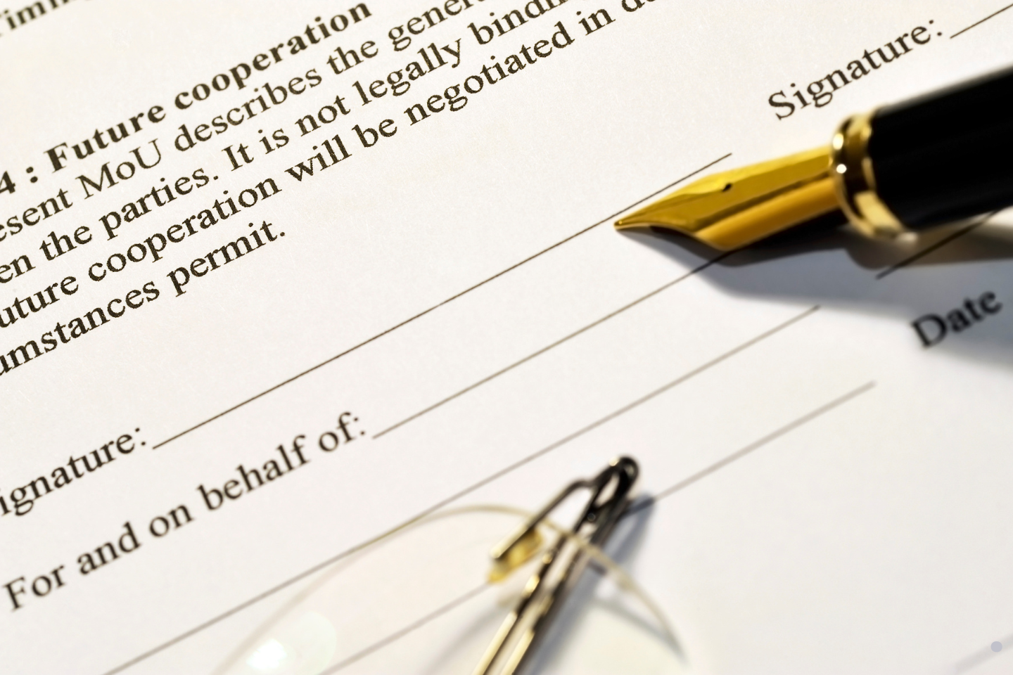 Close-up of a contract signature line with a fountain pen resting above it. 