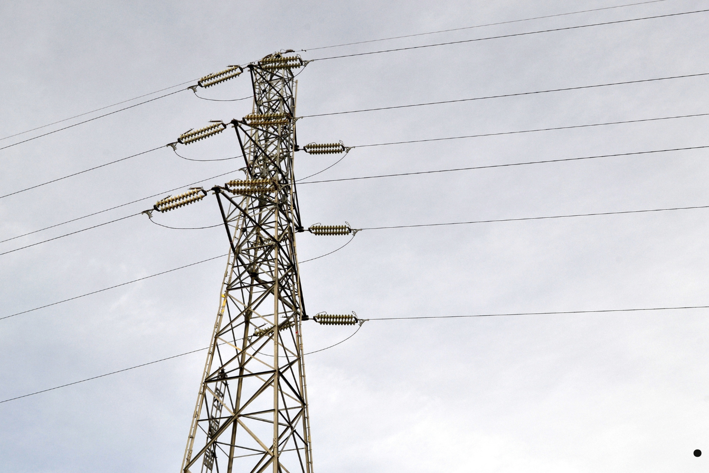 High-voltage power transmission tower with electrical lines against the sky.