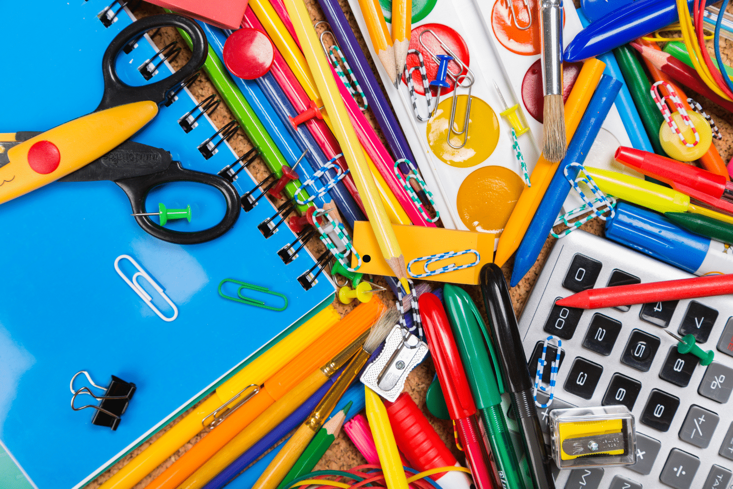 Colorful assortment of school supplies including pens, pencils, scissors, and notebooks.