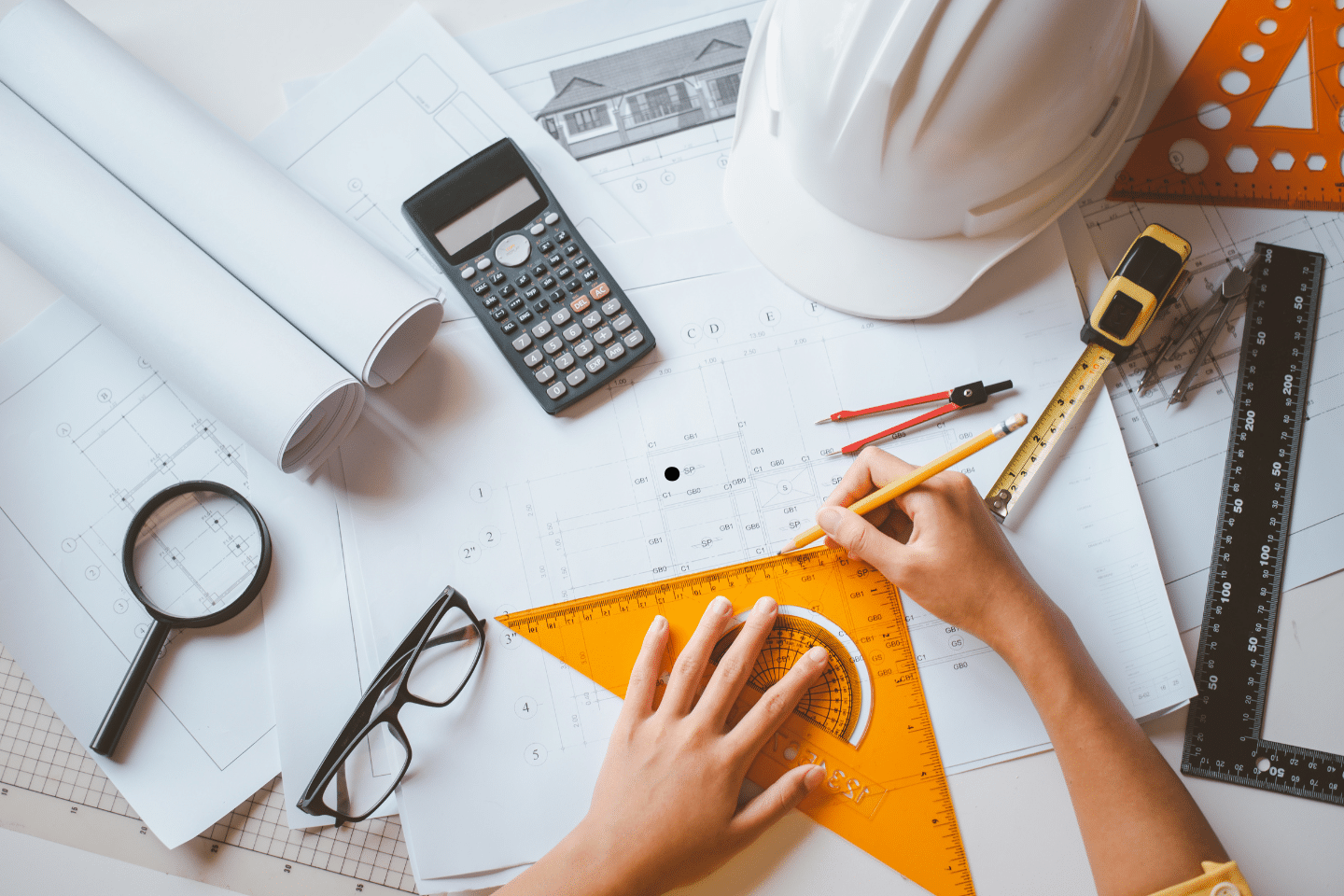 Architect’s workspace with rolled blueprints, hard hat, calculator, and drafting tools.