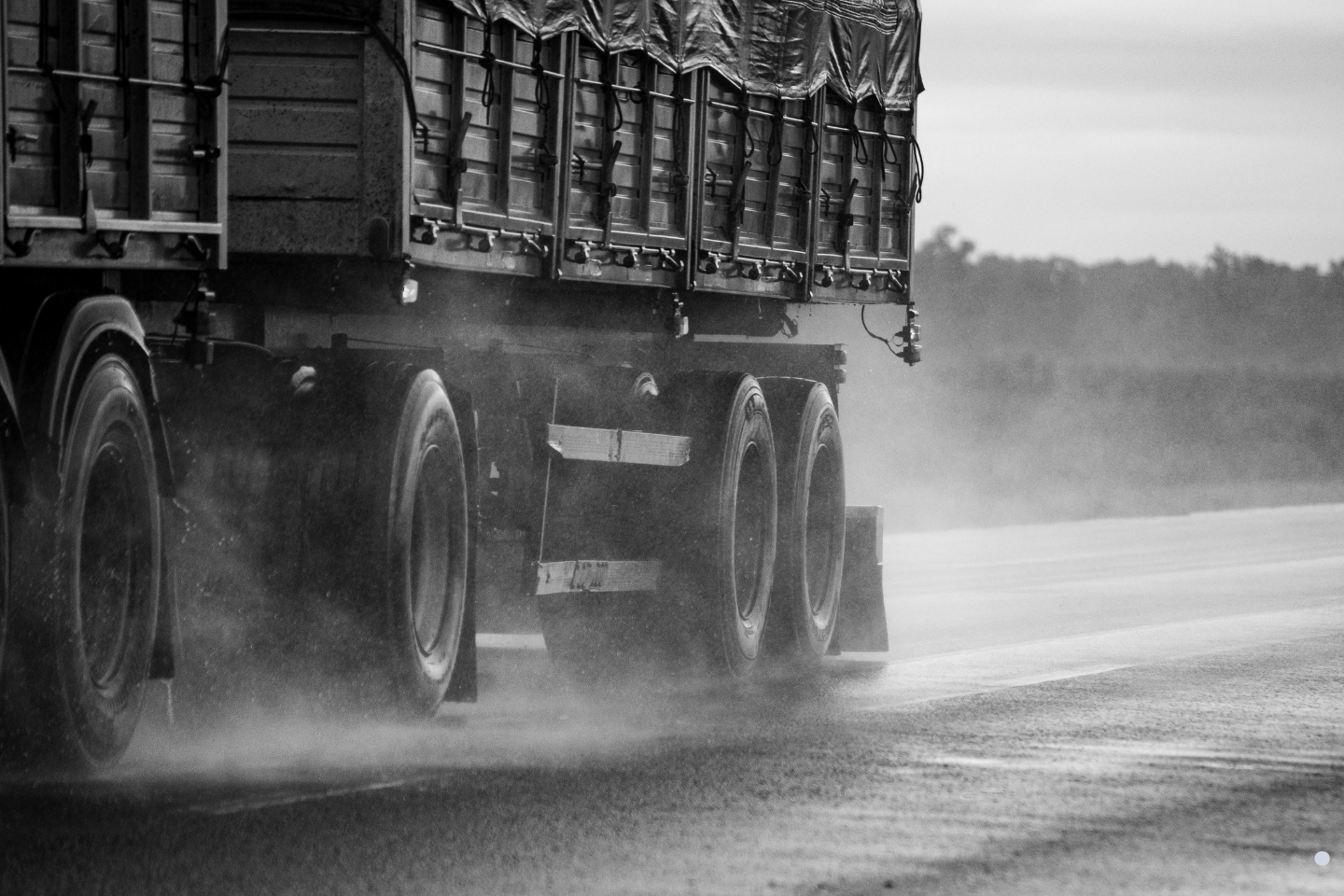 Close-up of a heavy hauling truck driving on a wet roadway, representing commercial transport operations requiring trip permits.