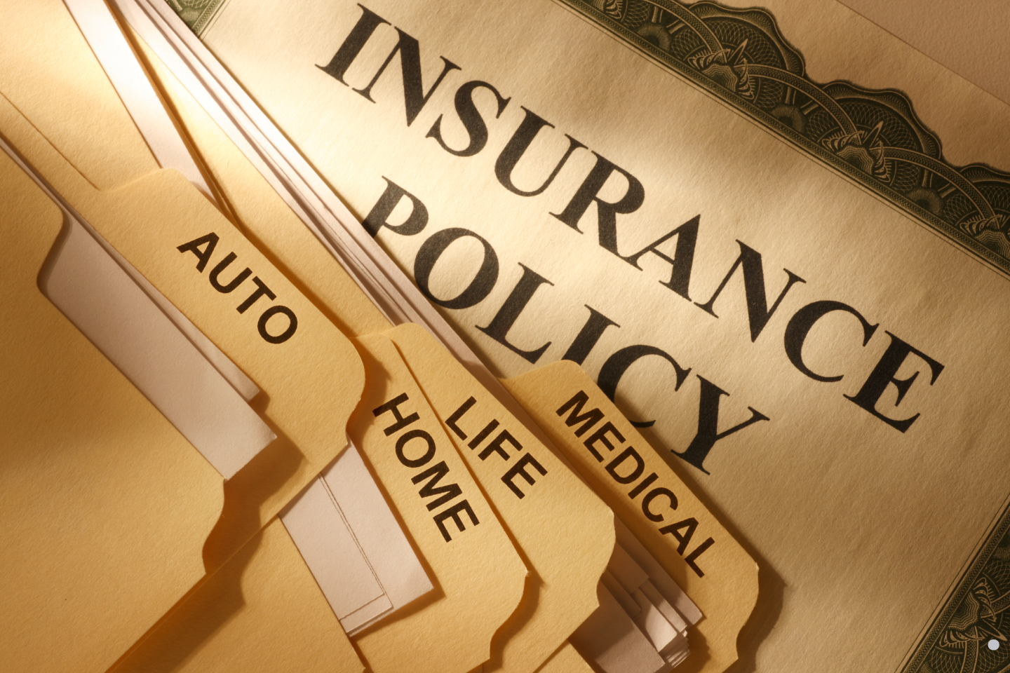 Close-up of organized insurance policy folders labeled auto, home, life, and medical.