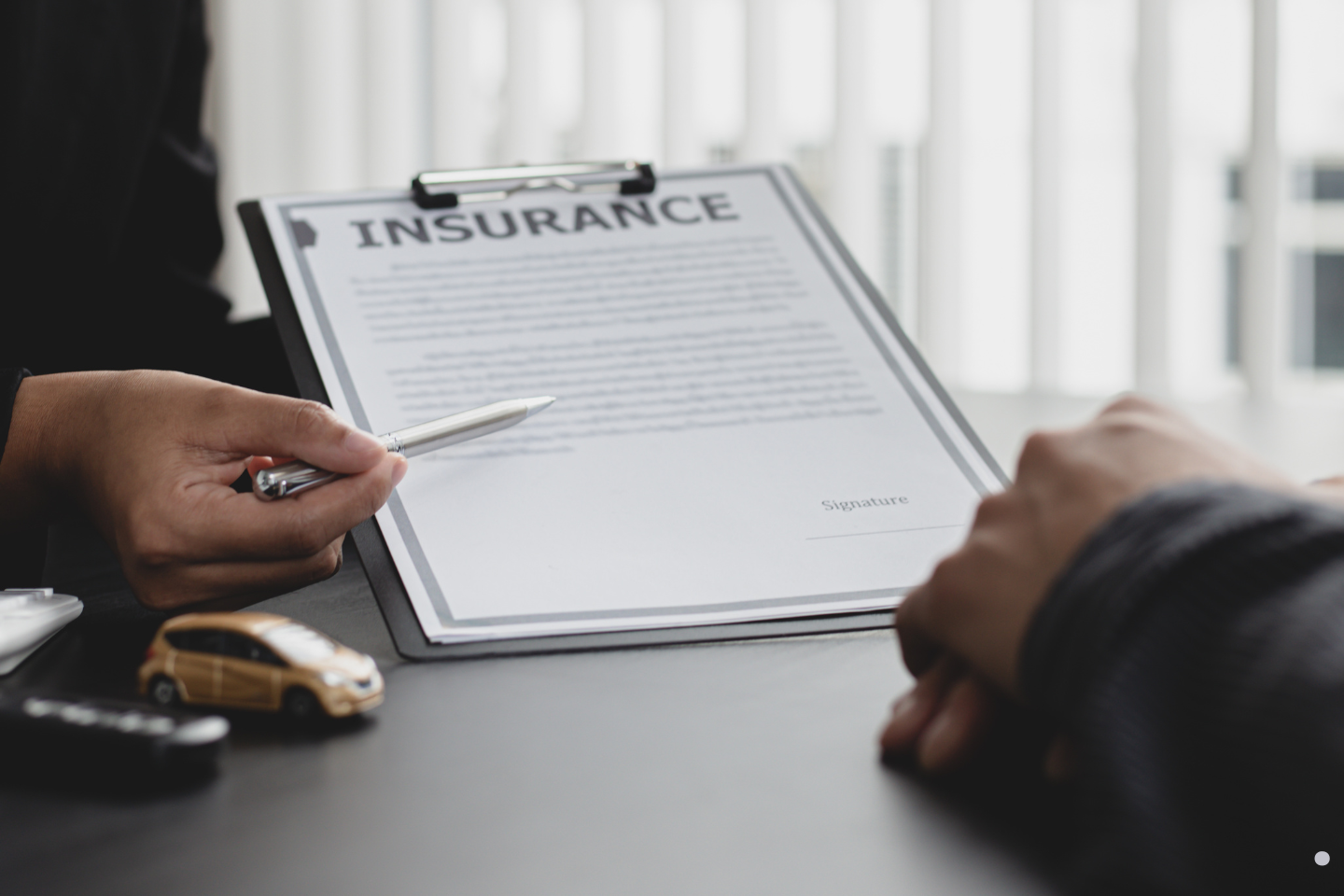 Person reviewing and discussing an insurance document on a clipboard.