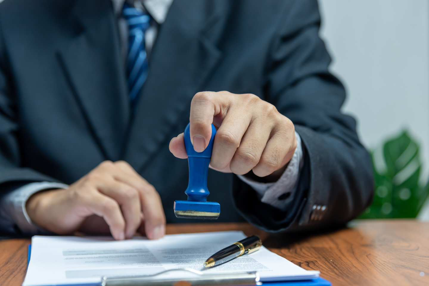 A professional in a suit pressing a blue stamp onto a document.