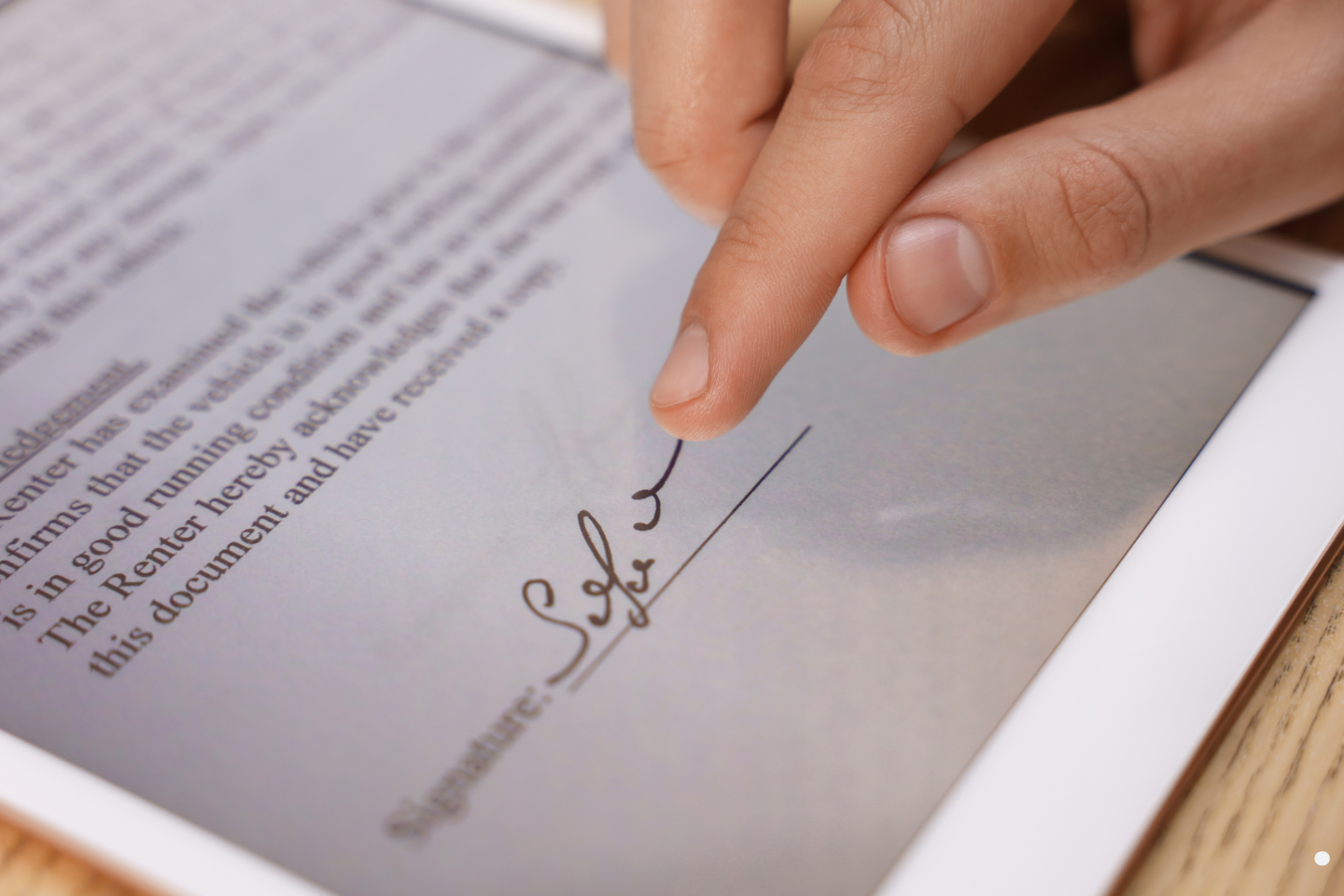 Person signing a digital document on a tablet screen.