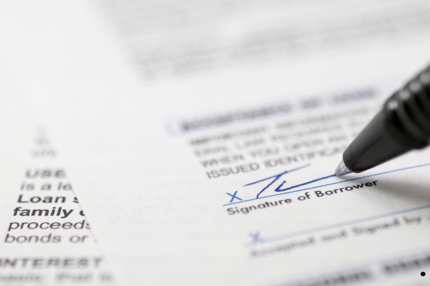 A close-up of a pen signing a borrower’s signature line on a document.