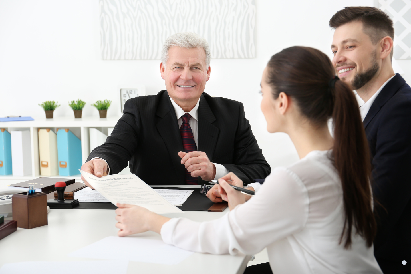 Business professional presenting legal documents to a couple during a surety bond or contract consultation.