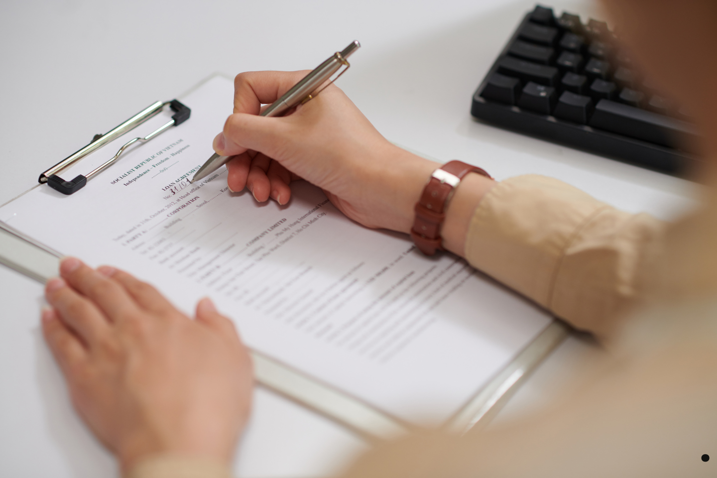 A person signing a document on a clipboard with a pen.