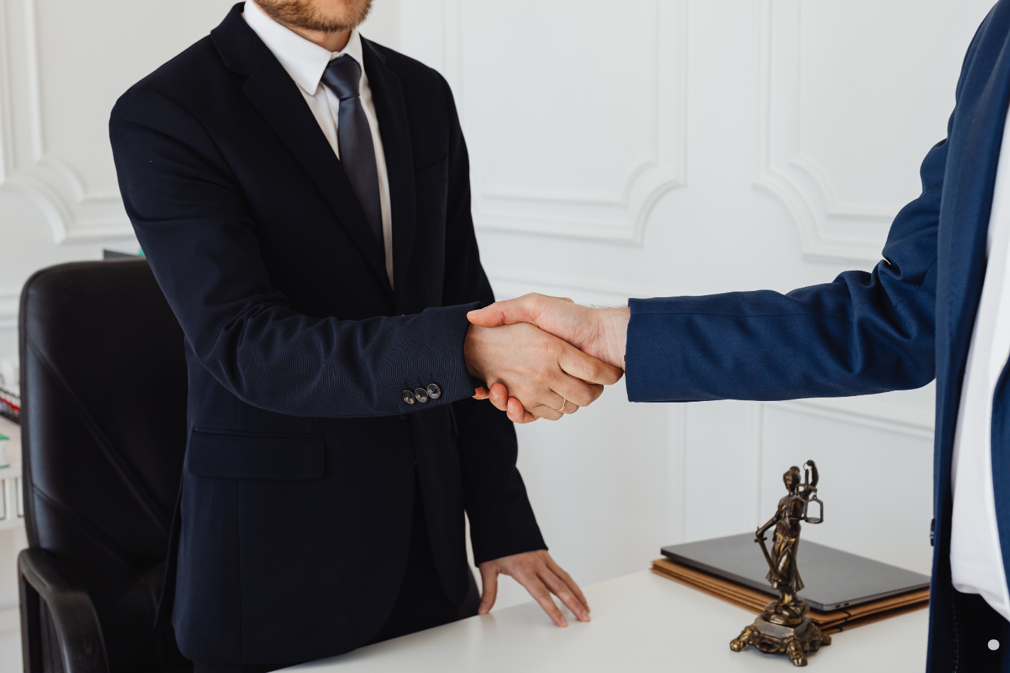 Two business professionals shaking hands in a formal office setting.