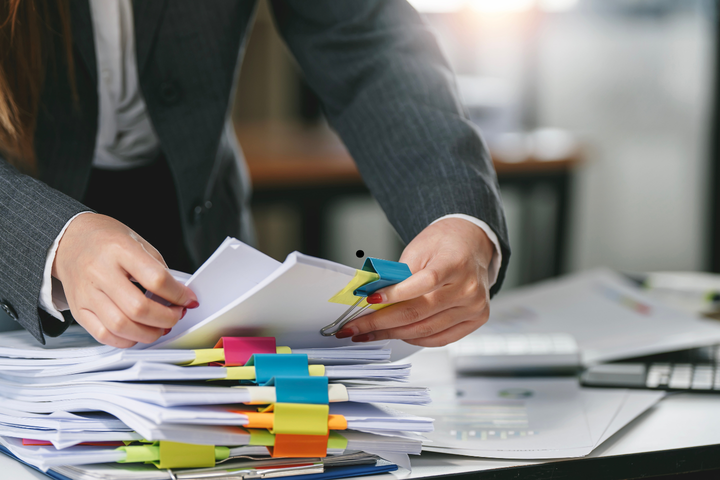 Professional organizing a large stack of paperwork with colorful binder clips.