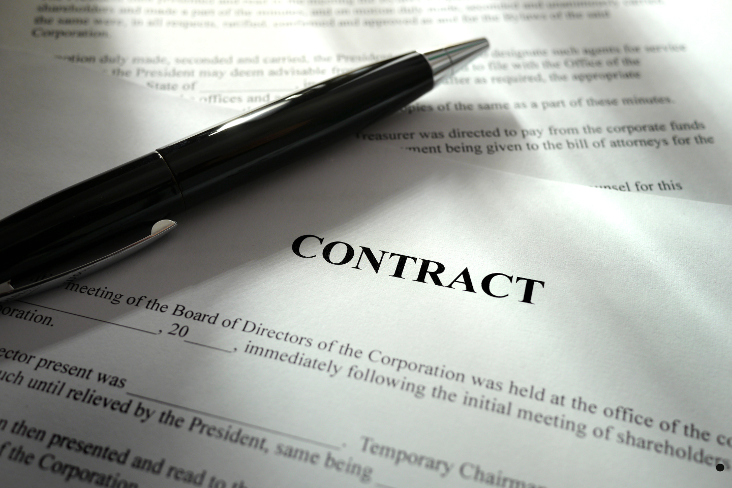 A black pen resting on a printed contract document in soft lighting.