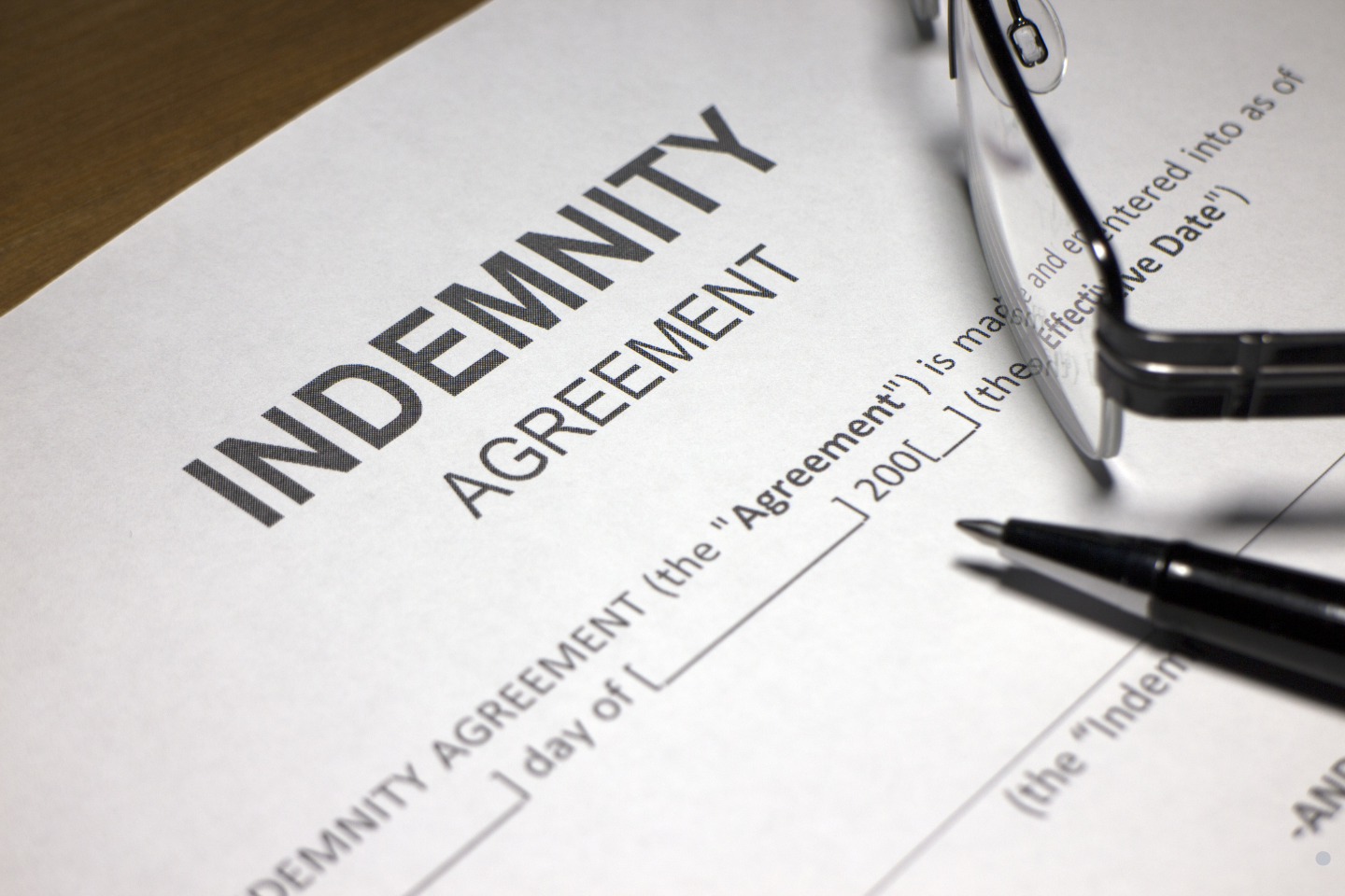 • Close-up of an indemnity agreement document with a pen and eyeglasses.