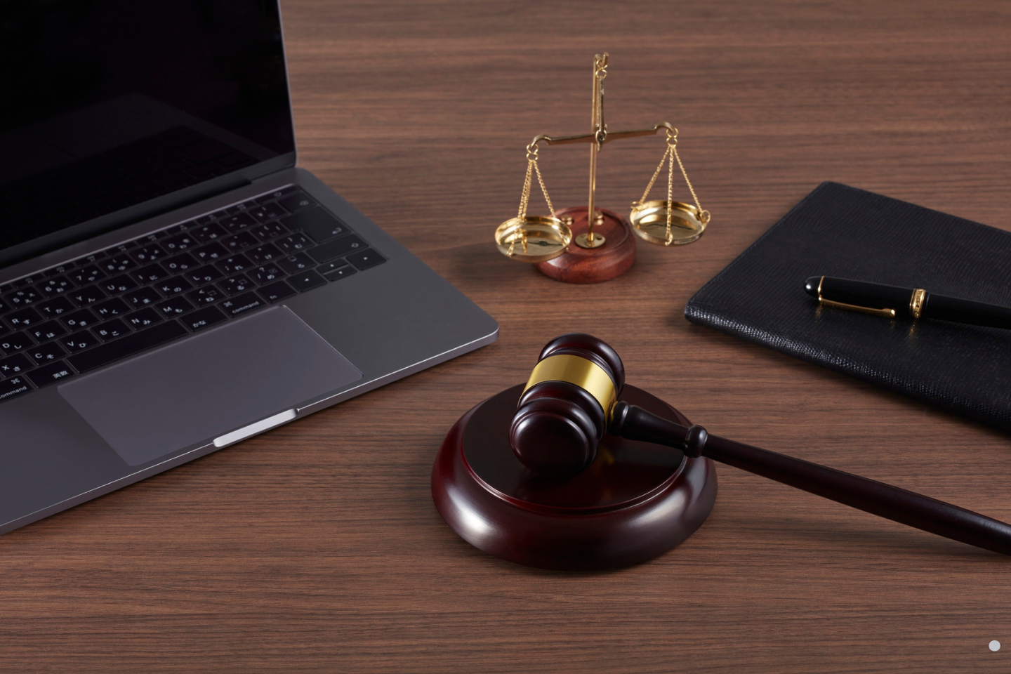 A courtroom-themed desk with a laptop, gavel, scales of justice, and pen arranged neatly.