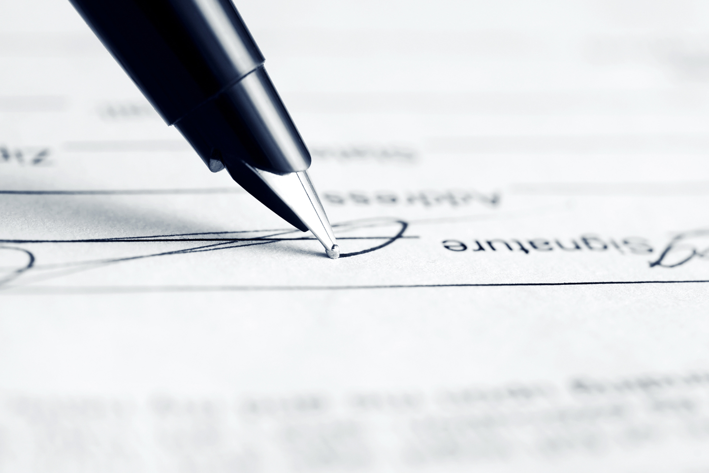 Close-up of a pen signing a signature line on a formal document.
