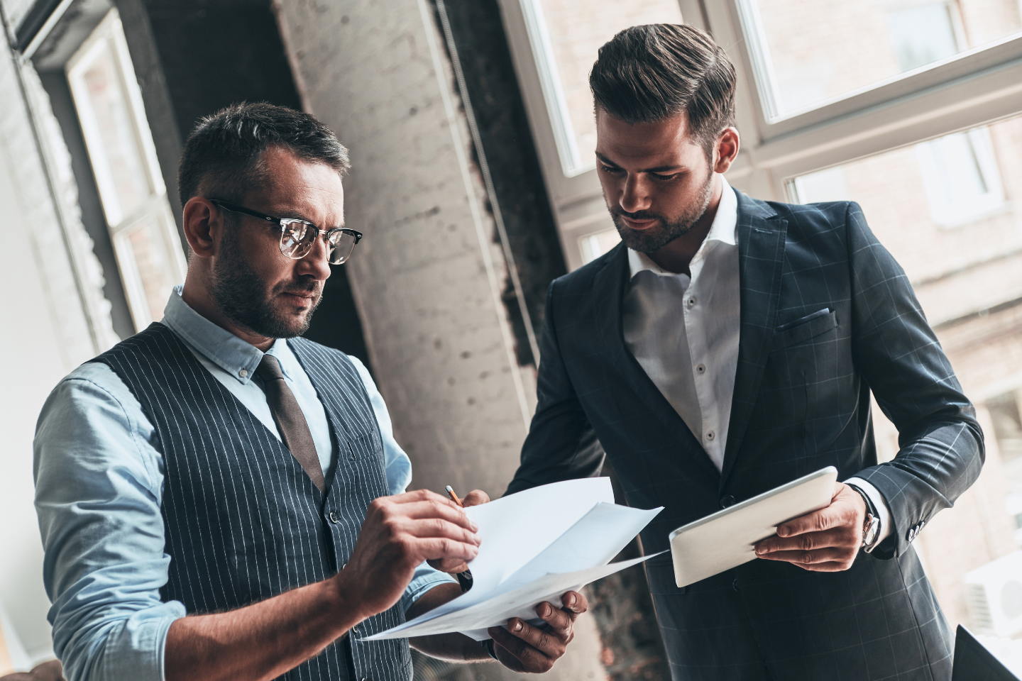 Two business professionals reviewing documents together near a window.