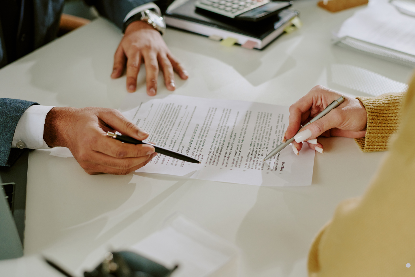 Two individuals reviewing and discussing a contract together at a desk.