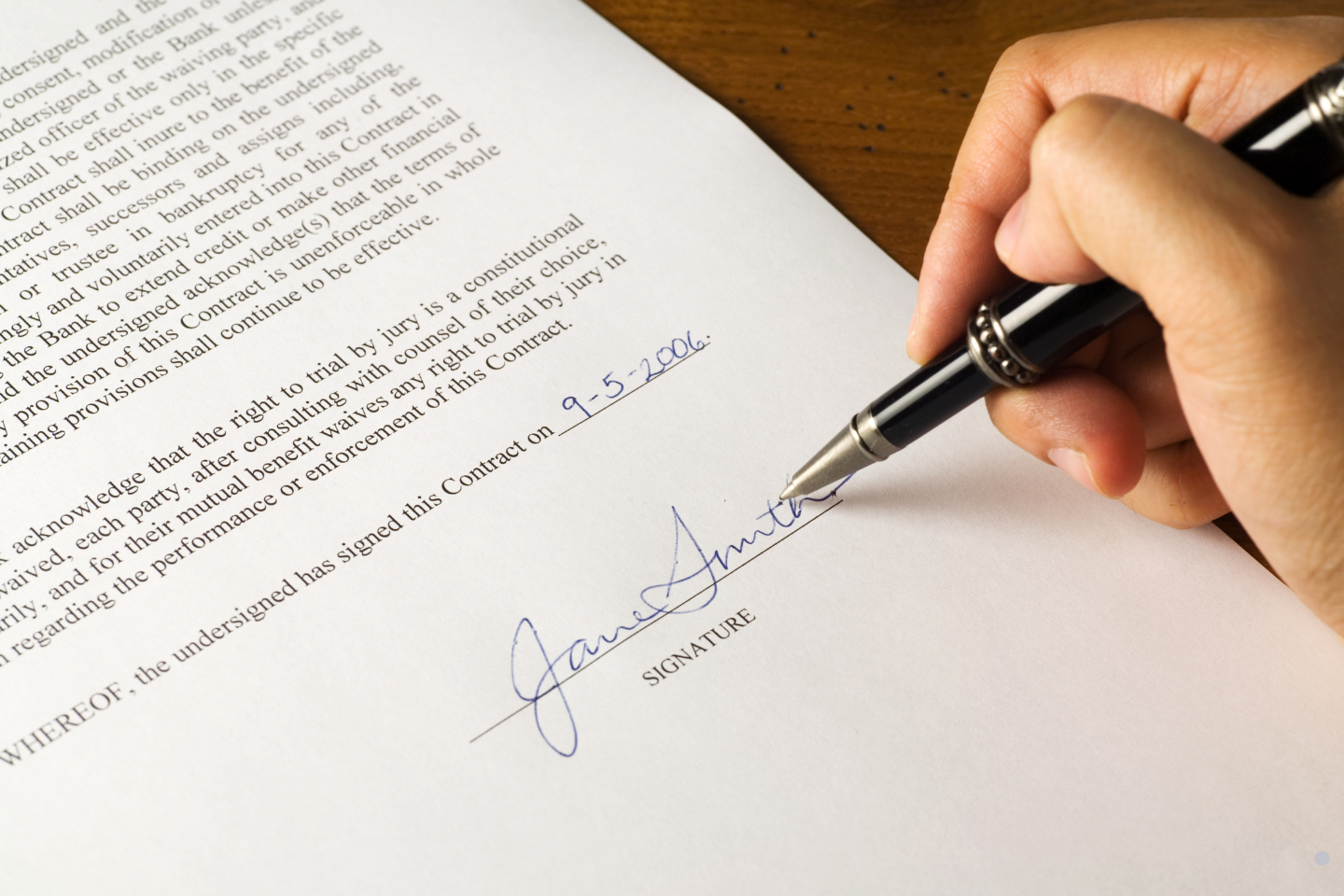 Hand signing a formal contract document with a pen.