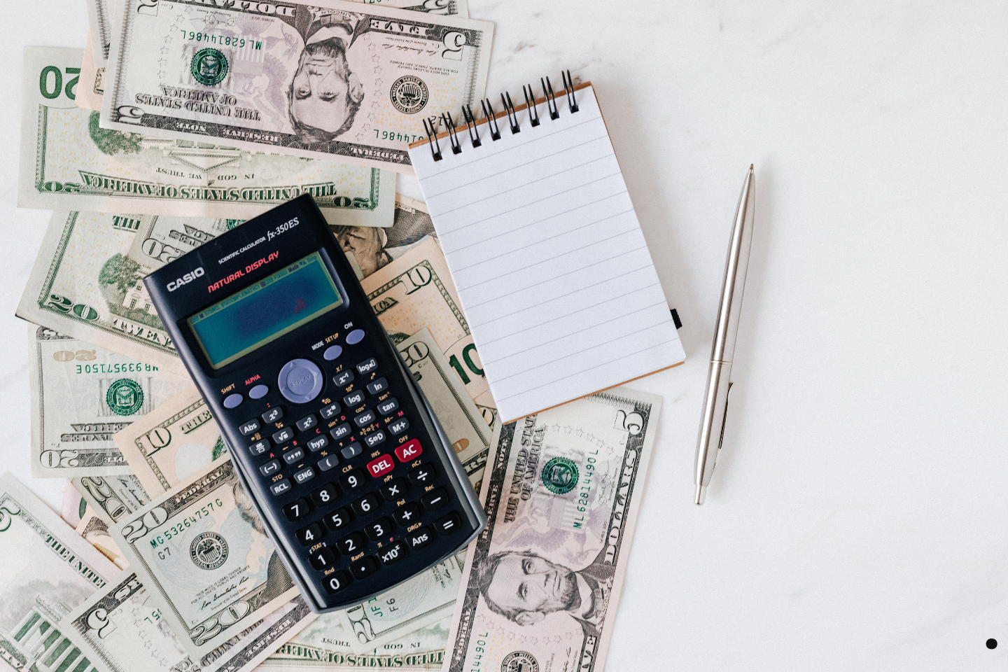 Calculator, notepad, pen, and scattered cash representing financial planning and expenses.