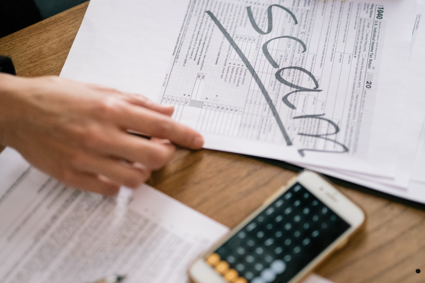 Hand reviewing paperwork marked with the word “scam” in large letters.