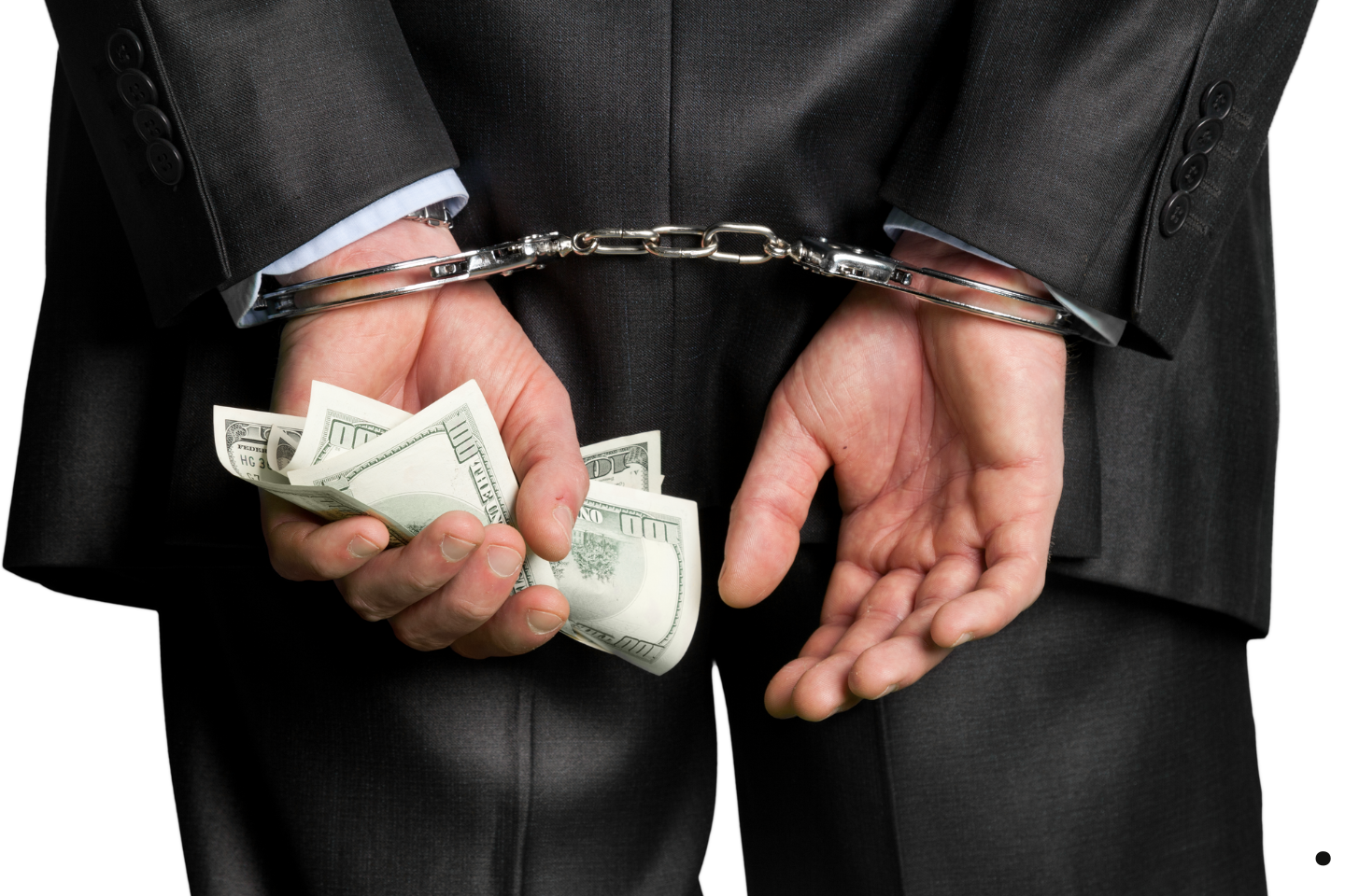 Businessman in handcuffs holding a stack of cash behind his back.