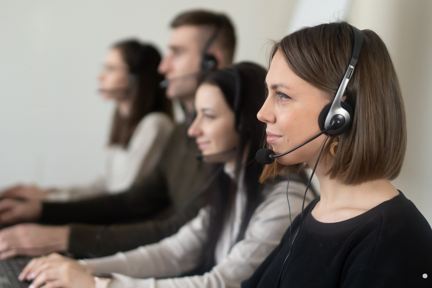 • Focused team of customer support representatives using headsets and working at their computers.