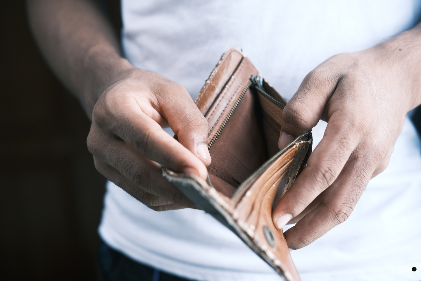 A person holding an empty wallet, symbolizing financial hardship.