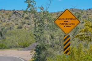 Yellow road sign that reads 'Misconceptions About Performance Bonds' on a desert road in Goodyear, Arizona, emphasizing the importance of clearing up bond misconceptions for local contractors.